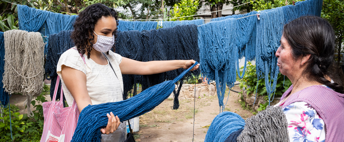 Fabiola Lara, GED'14, examines threads with one of the women artisans in Oaxaca, Mexico, an examples of tlali•pani’s offerings