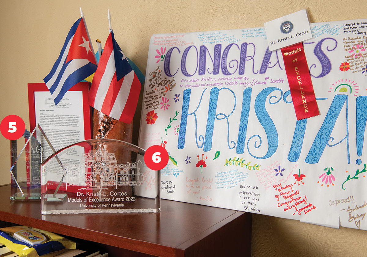 Krista's 2021 Lambda Theta Alpha Award, 2023 Penn Model of Excellence Award and poster and mini Puerto Rican flags