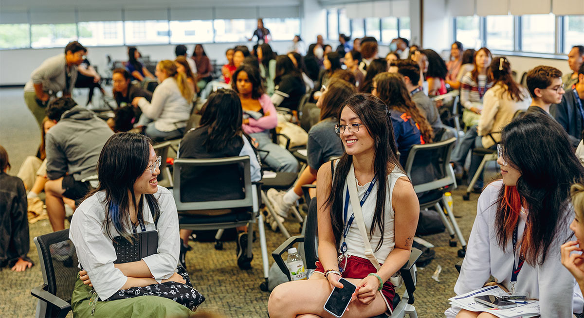 Penn GSE students sitting in groups, smiling and socializing during an orientation