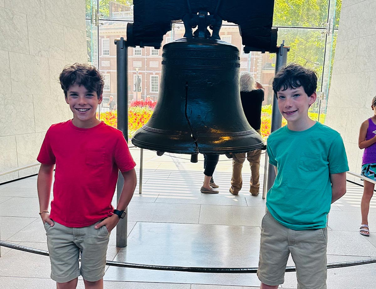 Dean Katharine Strunk's fraternal twin sons Bryce and Cole pictured standing beside the Liberty Bell