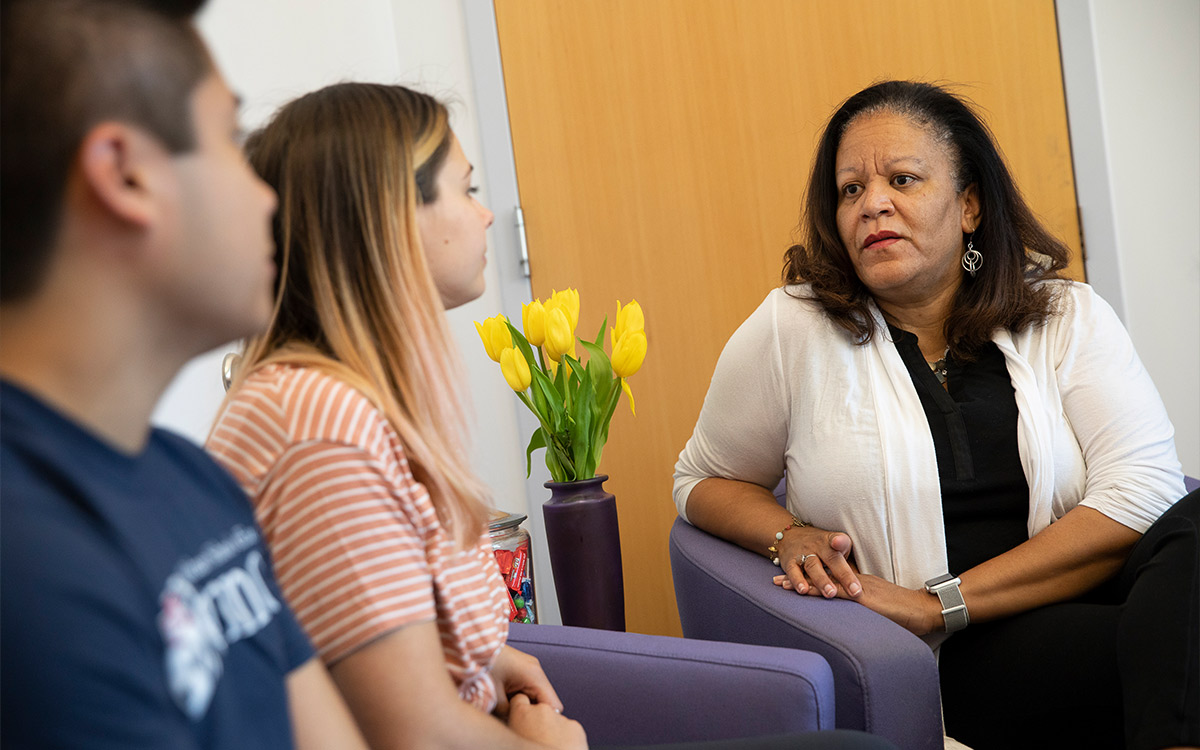 Senior Lecturer Marsha Richardson sits in an arm chair looking focused as she meets with two Penn GSE counseling students