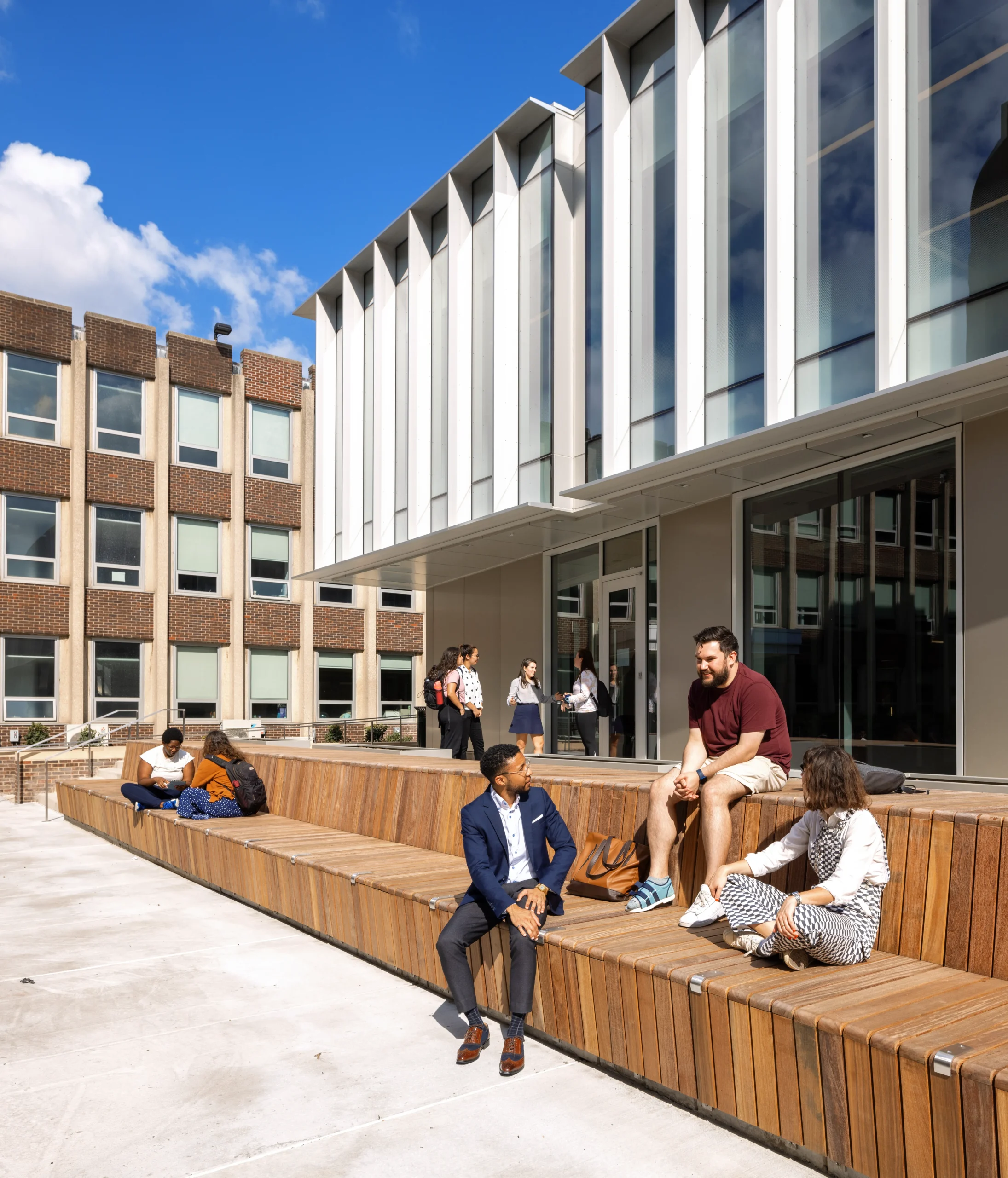 Penn GSE's brand new courtyard with modern wood seating area and students involved in conversation and socializing