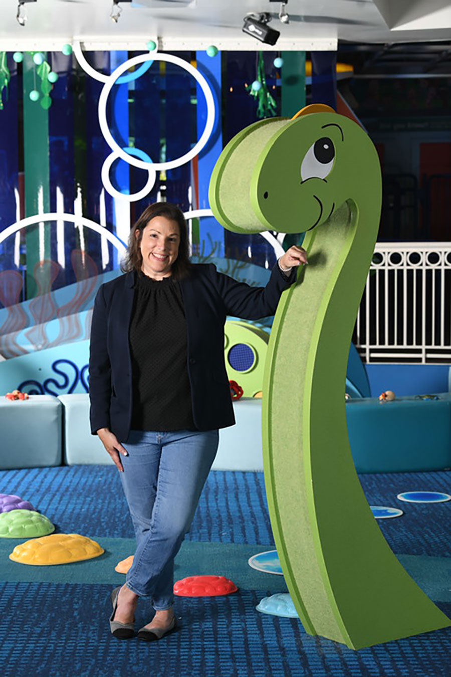 Rachel Demma smiling next to dinosaur statue made of wood