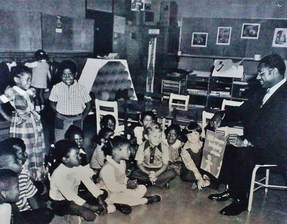 old photograph of Superintendant Marcus Foster reading to children