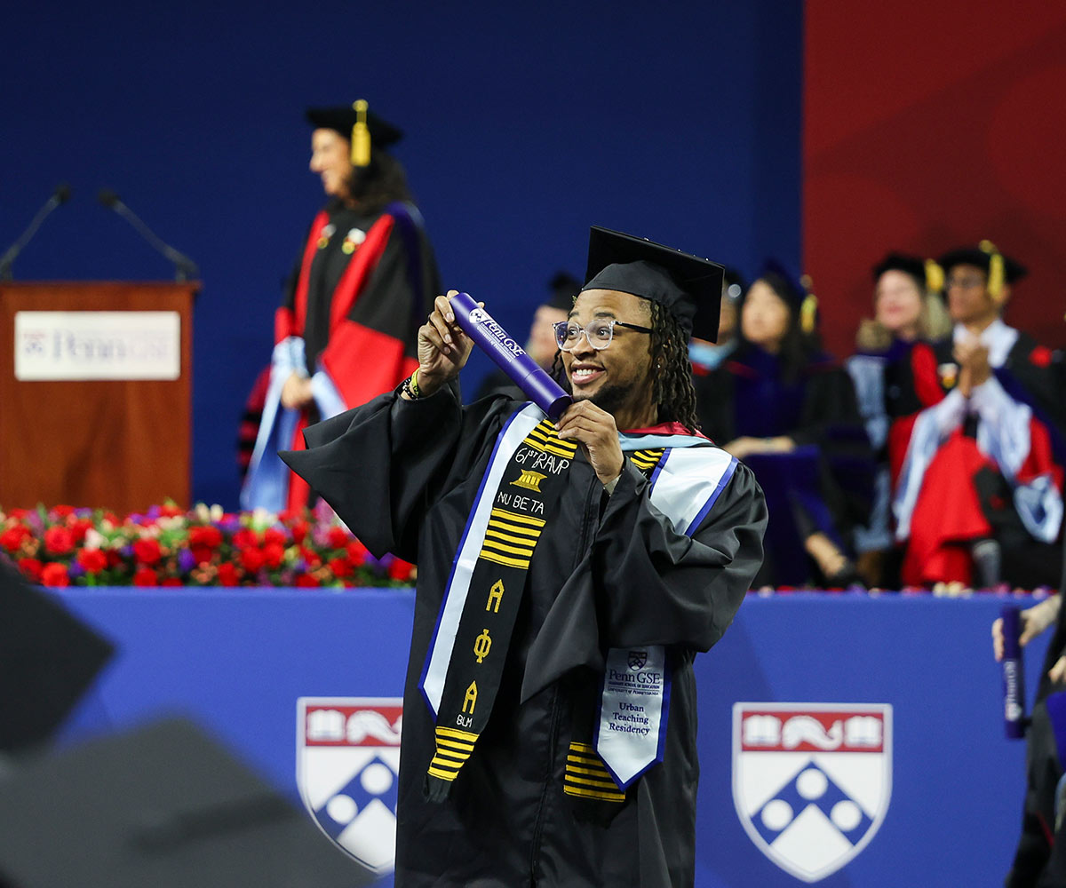 Penn GSE graduate student holding up diploma